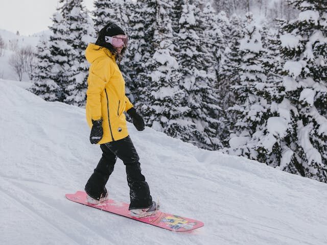 photo person in winter clothing riding a snowboard