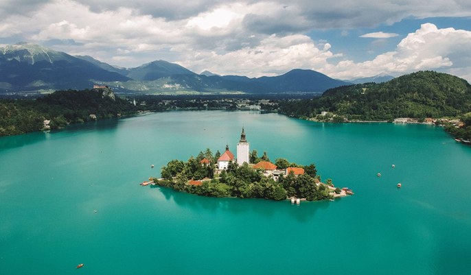 Aerial view of Lake Bled in Slovenia, showcasing its stunning blue waters and the iconic island church in the center.