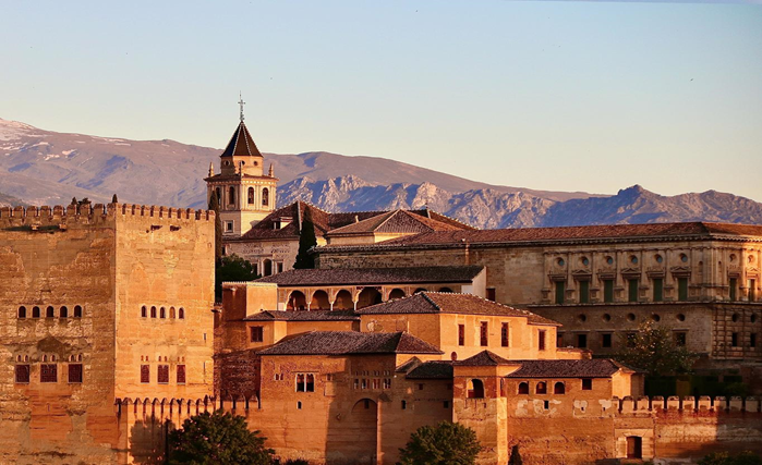 The Alhambra Palace in Granada, Spain, showcasing intricate architecture and lush gardens under a clear blue sky.