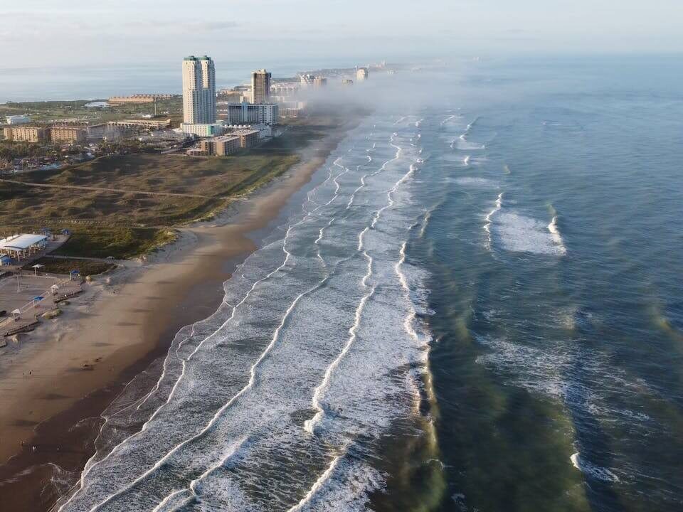 drone shot of waves crashing on the shore